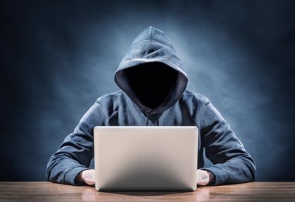 Shifty figure sitting at computer - hacking a website.